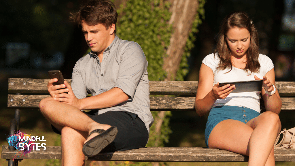 man and woman sitting on bench distracted by mobile phones and tablets