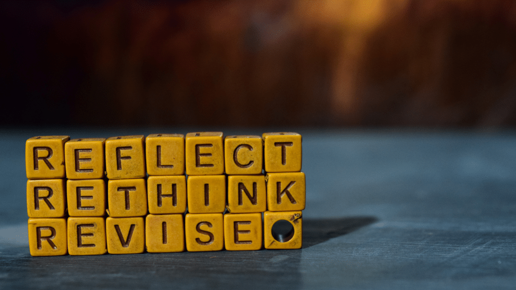 photo of orange dice that say reflect, rethink and revise